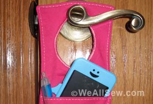 Have a habit of misplacing your keys. Losing your iPod? Forgetting your coupons? Now, with this handy organizer, all your little necessities are in one convenient spot when you're ready to head out the door - right on the door knob! How to Make a Door Organizer Supplies 1/3 yard or heavyweight fabric such as twill, canvas, or denim 1/3 yard of fusible interfacing Coordinating thread Scissors Water-soluble marking pen or tailor's chalk Ruler 1/4" presser foot (BERNINA Patchwork Foot #37 or Patchwork Foot with Guide #57) Download and print the keyhole template: [download id="88"] Step 1) Prepare the fabric pieces. Cut from the heavyweight fabric: Two 5" x 11" rectangles for the organizer body One 5" x 12" rectangle for the large pocket One 5" x 7" rectangle for the small pocket One 6" x 7" rectangle for the hanging pocket Fuse interfacing to the wrong side of both 5" x 11" fabric rectangles following the manufacturer's directions. How to Make a Door Organizer Cut the keyhole: Measure down 1" from the top edge of one 5" x 11" rectangle. Center the top of the keyhole template on this mark. Trace the template. Cut along the traced line. Repeat for the second 5" x 11" rectangle. How to Make a Door Organizer Step 2) Make the large and small pockets. With wrong sides together, fold the large pocket in half to create a 6" x 5" rectangle. Topstitch close to the folded edge. How to Make a Door Organizer Place the large pocket on top of the right side of one 5" x 11" rectangle, matching the raw edges along the sides and bottom edges. Baste in place. How to Make a Door Organizer With wrong sides together, fold the small pocket in half to create a 3 1/2" x 5" rectangle. Topstitch close to the folded edge. Place the small pocket on top of the large pocket, matching the raw edges along the sides and bottom edges. Baste in place. How to Make a Door Organizer Step 3) Make the hanging pocket. With wrong sides together, fold the 6" x 7" rectangle in half lengthwise. Press. How to Make a Door Organizer Unfold the strip and then fold the long raw edges to the center fold line. Press. Refold the strip along the center crease. Topstitch close to both long edges. How to Make a Door Organizer Fold under 1" on both edge of the finished 7" strip. Measure up 1-1/4" from the lower edge on the right side of the second 5" x 11" piece. Center the bottom of the strip on this mark. How to Make a Door Organizer Sew close to the folded ends of the strip, then again 1/2" away from the first stitching. How to Make a Door Organizer Step 4) Construct the door organizer. With right sides together, place the two 5" x 11" rectangles together, matching the raw edges and the keyhole opening. How to Make a Door Organizer Stitch around the entire rectangle, leaving the keyhole open. Do not stitch around the keyhole area! Clip the corners. How to Make a Door Organizer Turn the organizer right side out through the keyhole opening. Press. How to Make a Door Organizer Topstitch close to the finished edges. How to Make a Door Organizer Baste the raw edges of the keyhole opening together. How to Make a Door Organizer Satin stitch close to the keyhole edges. Position the fabric so the needle goes just barely to the right of the raw edges and encloses them in stitches. Tip: A satin stitch is a zigzag stitch with a very short stitch length, so the stitches are very close to each other. How to Make a Door Organizer How to Make a Door Organizer Fill your organizer with keys, pens, letters, etc. so you never leave home without your essentials! How to Make a Door Organizer