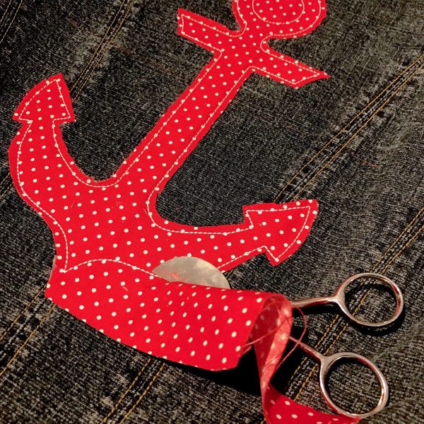 Remove the hoop from your machine, but leave the projected hooped. Trim around the cutting line, leaving a 1/8” seam allowance. Leave the inner circle at the top of the anchor intact for now. We’ll trim this out after the project is complete and unhooped to make it easier.