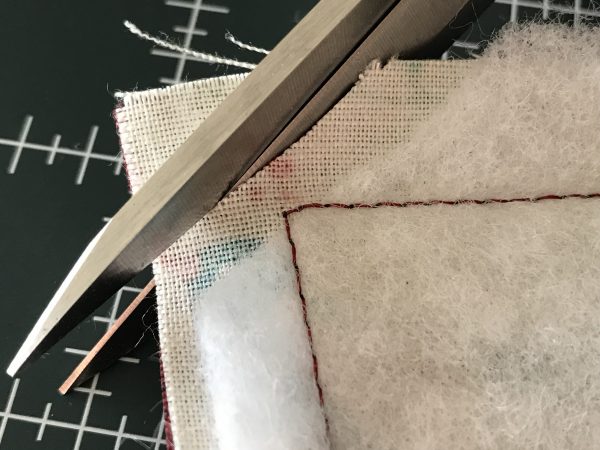 rim off the fabric corner points about 1/8” from corner stitching