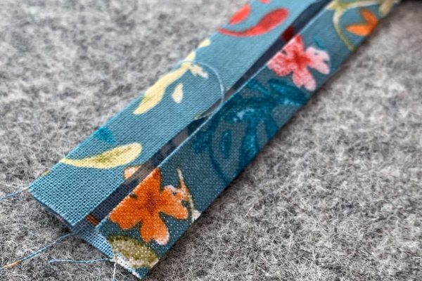 Fold long edges of strap to meet in middle and press