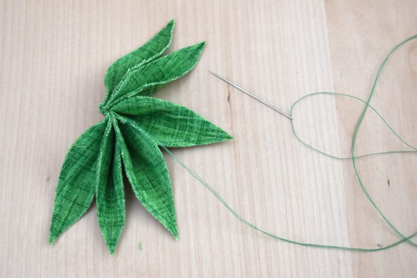 Pull back the two leaves on the top of the sandwiched bunches, and the two leaves on the bottom. Now tack stitch the two middle leaves together, sewing over where the thread is.