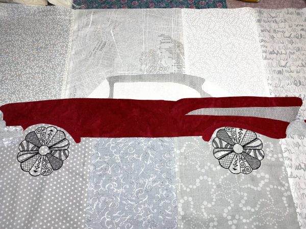 Alignment of car with embroidered wheels and fusing to prepared background fabric. 