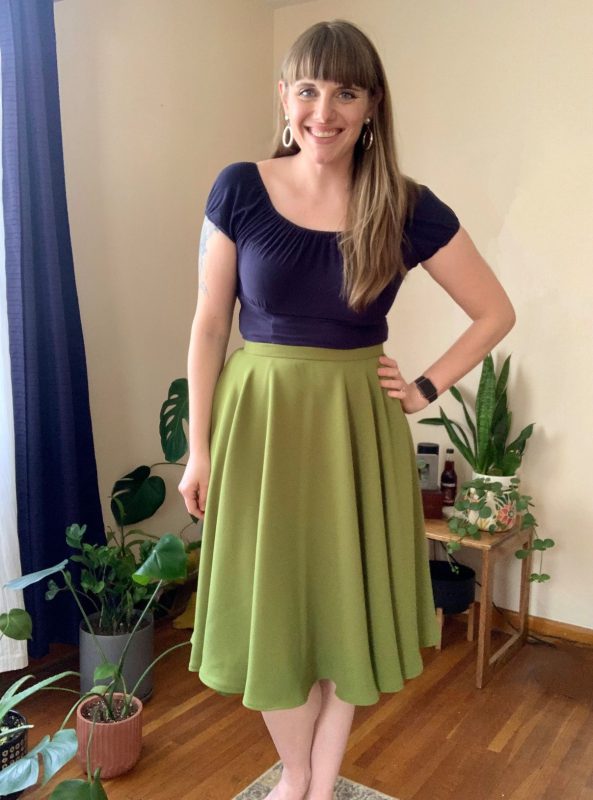 A white woman in a green circle skirt and a blue top