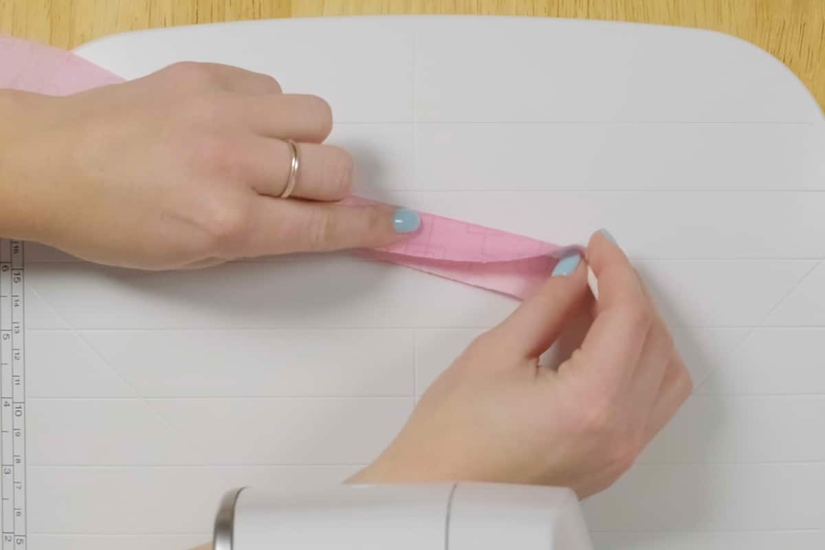 overhead view of pink fabric being wrapped around white cord