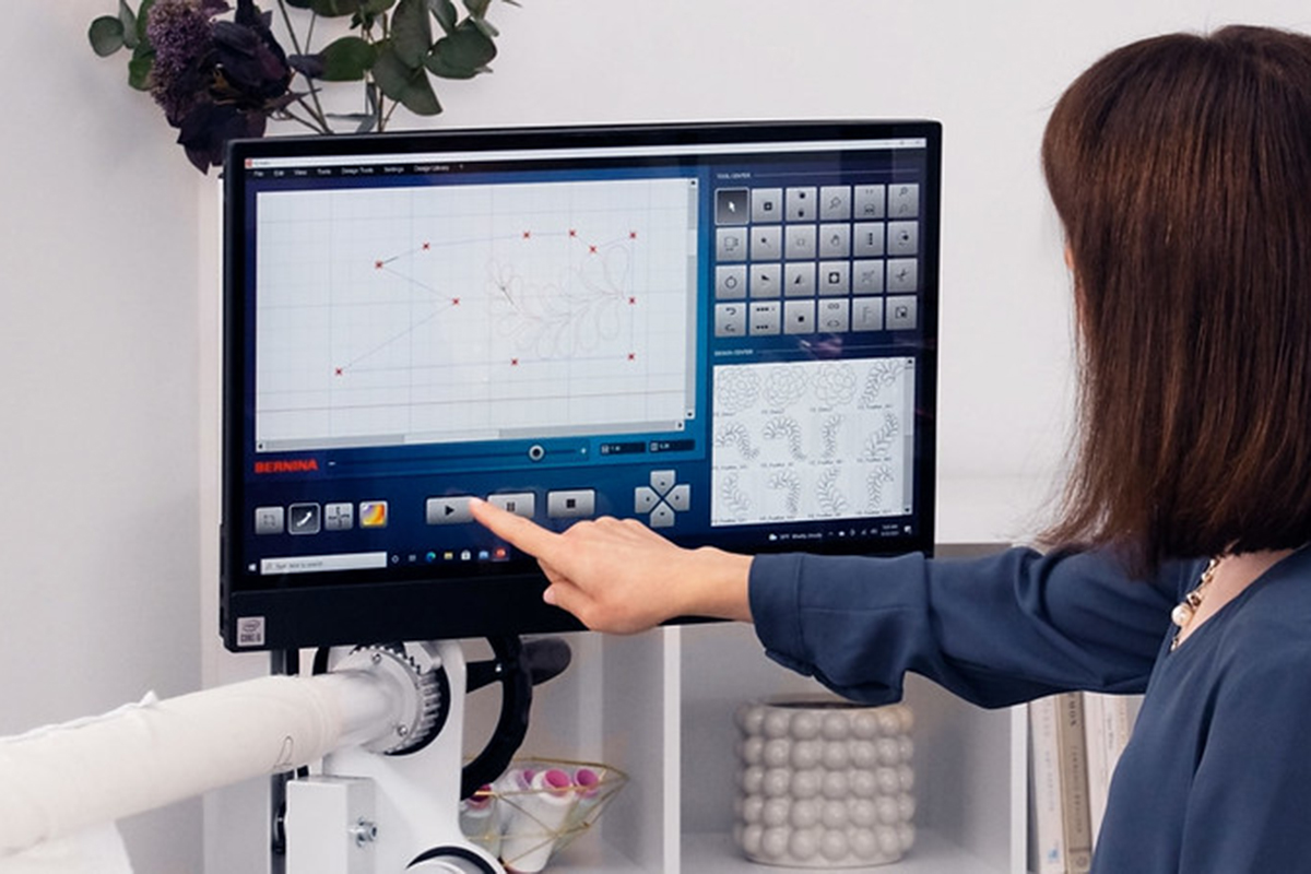 a woman pressing Play on the display screen of the BERNINA Q-matic.
