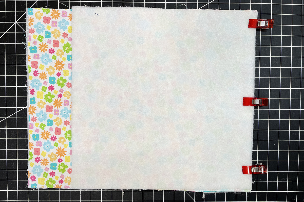overhead view of two squares of fabric clipped together.