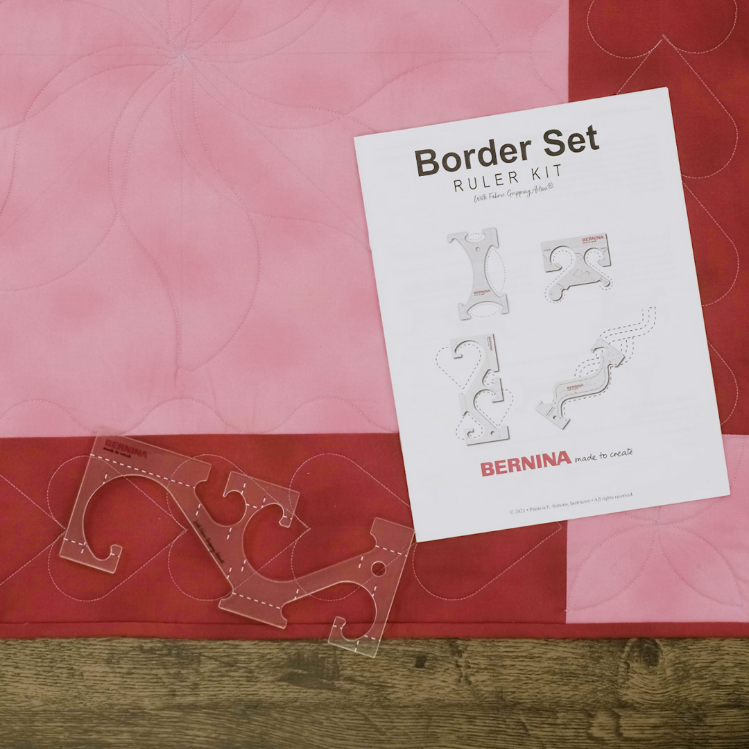 BERNINA Border Ruler Kit instruction manual on top of red and pink checkered quilt