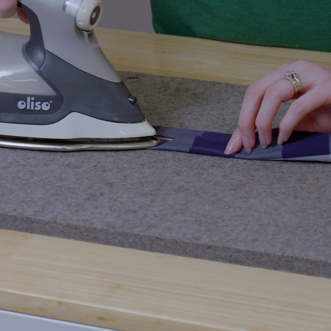 Iron pressing folded edges of 2-inch strip for apron straps