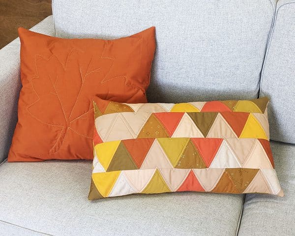 Two Fall-theme colored pillows on gray couch