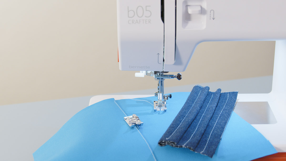 Heavy blue fabrics and presser feet arranged with the bernette 05 sewing machine.