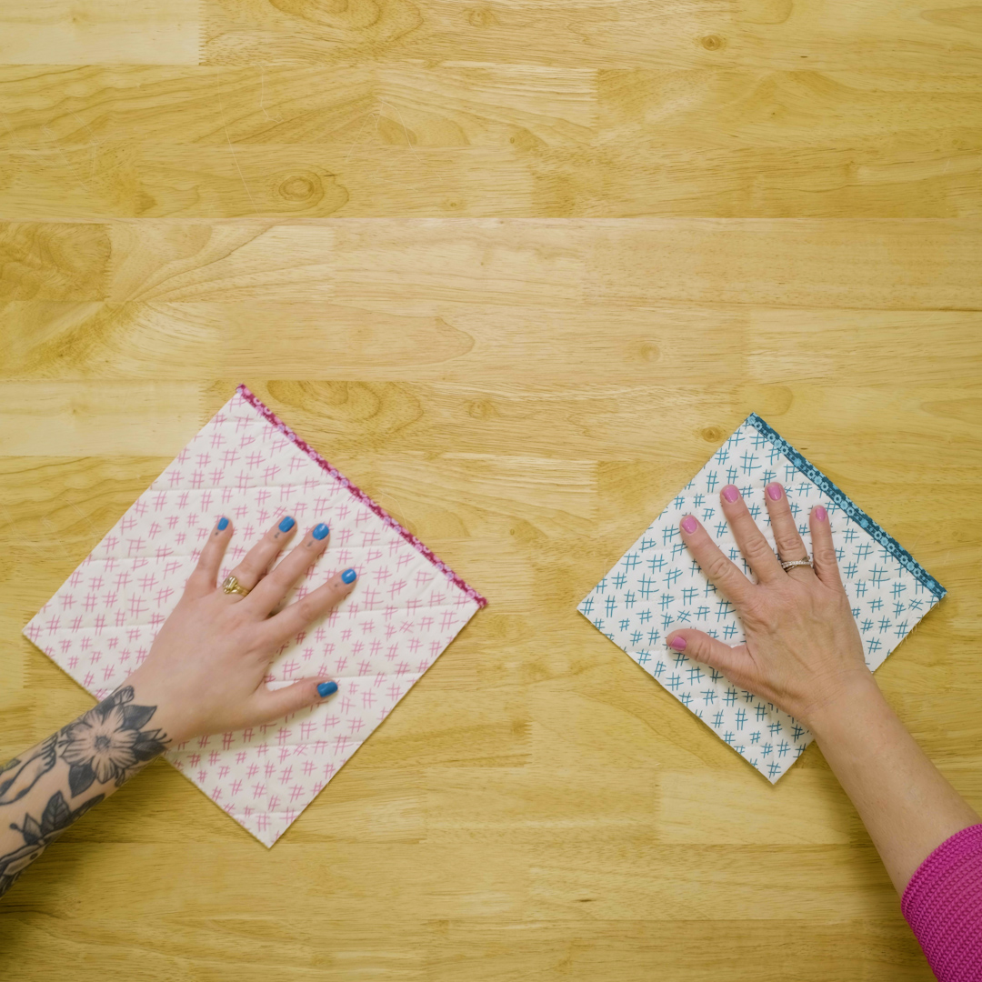 Overhead view of hands holding fabric samples on a wood table