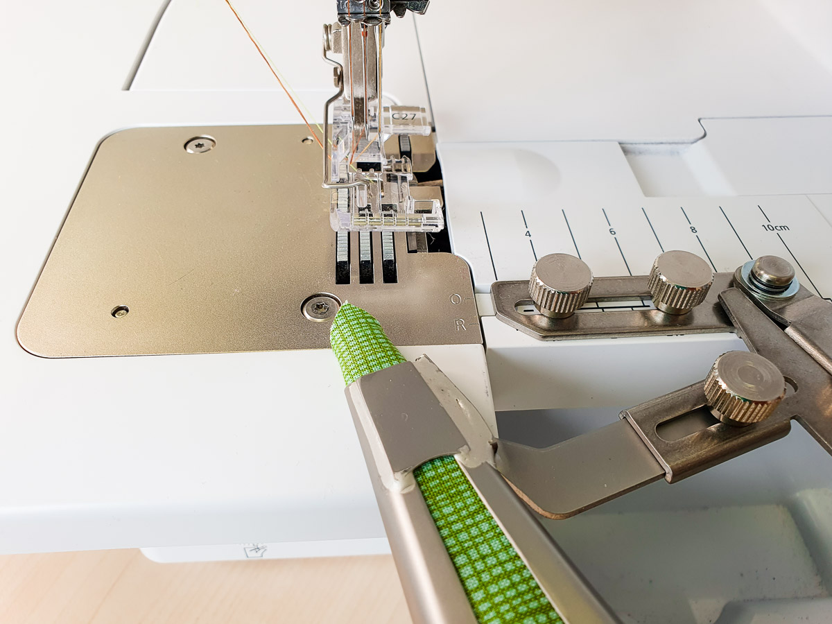 green fabric being fed through the Belt Loop Folder on the BERNINA L 890