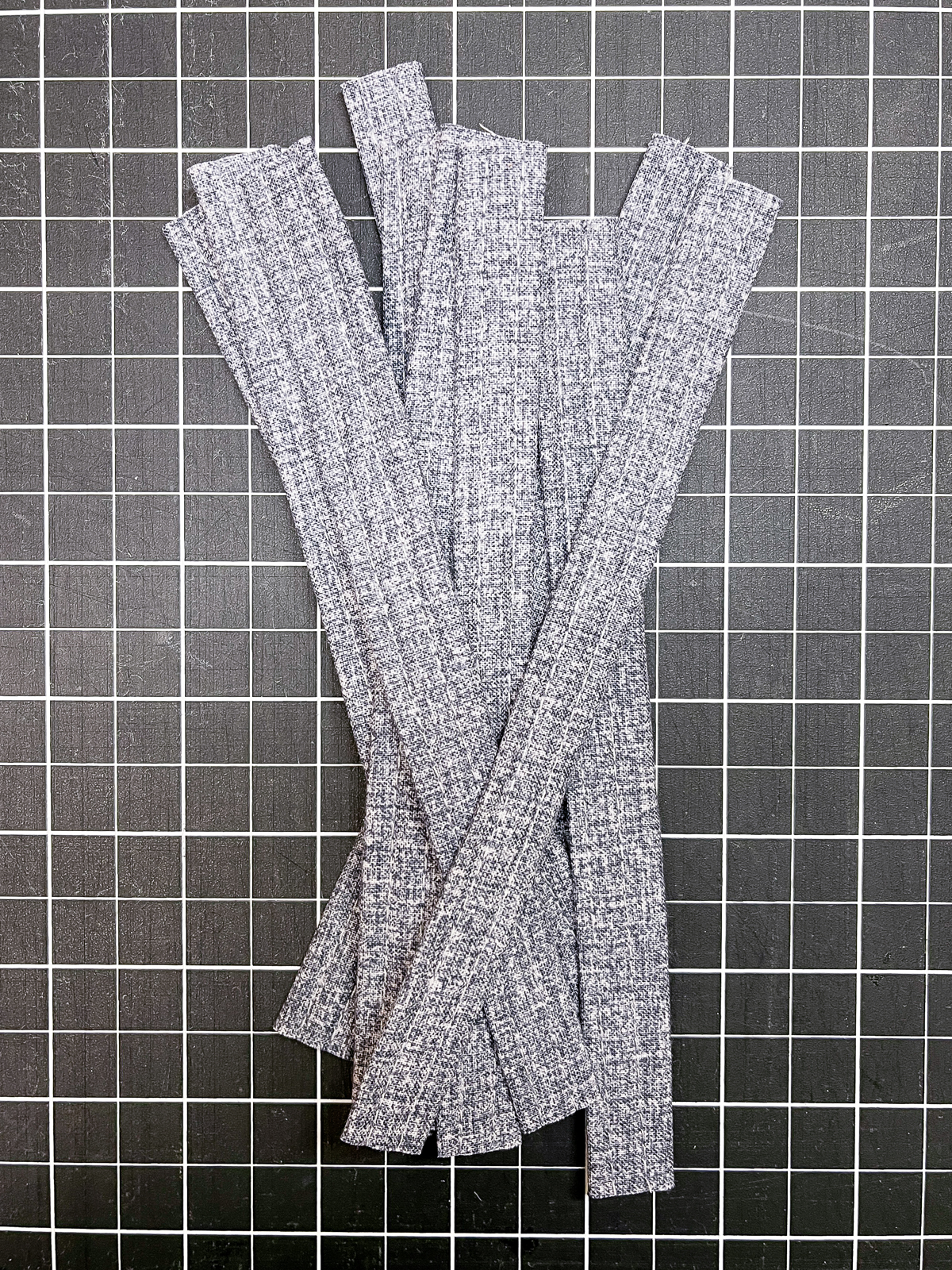 Arrangement of grey fabric strips on a black cutting board