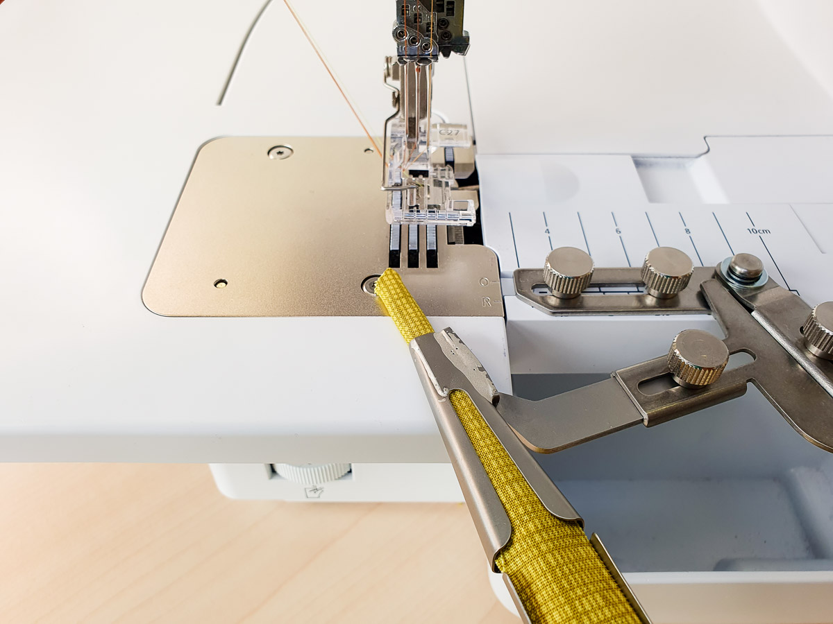 feeding yellow fabric through the Belt Loop Folder on the L 890