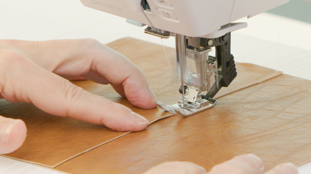 A person sewing a piece of leather