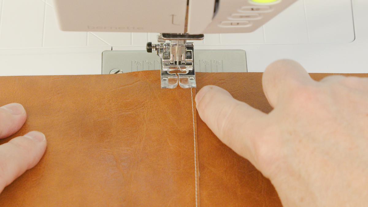 A person sewing a piece of leather