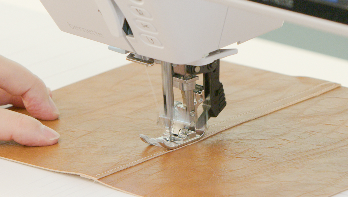 Close-up of sewing machine stitching brown leather fabric with precise seam