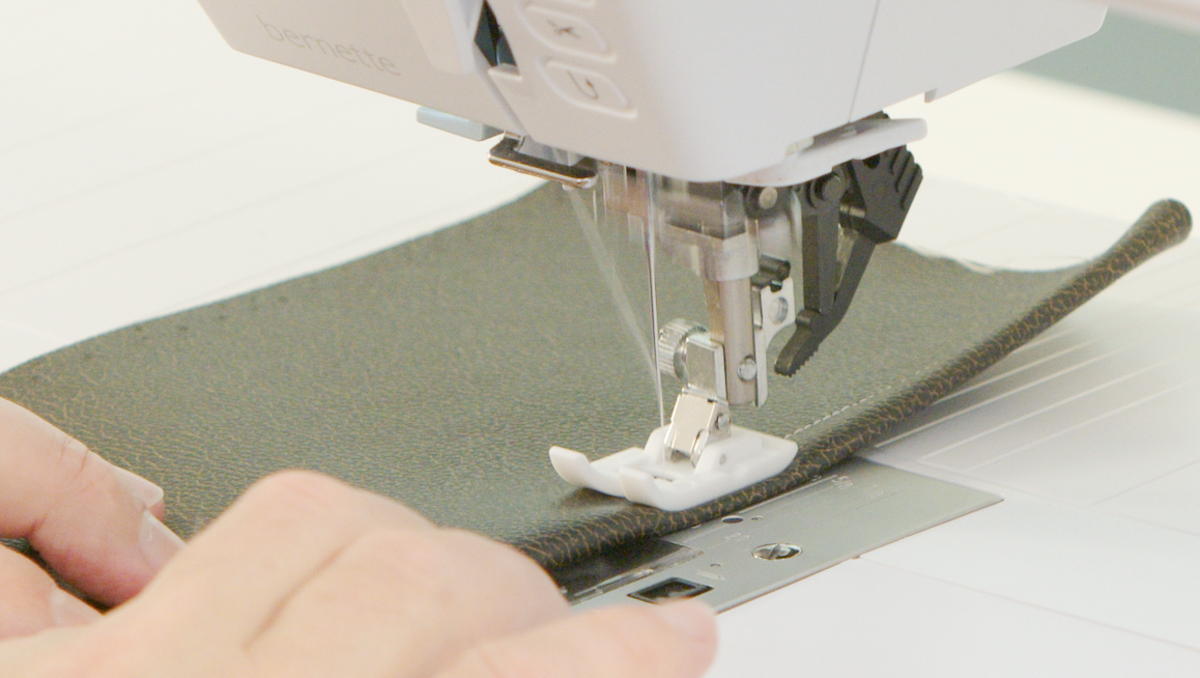 Sewing machine stitching textured black vinyl or leather with a non-stick presser foot.