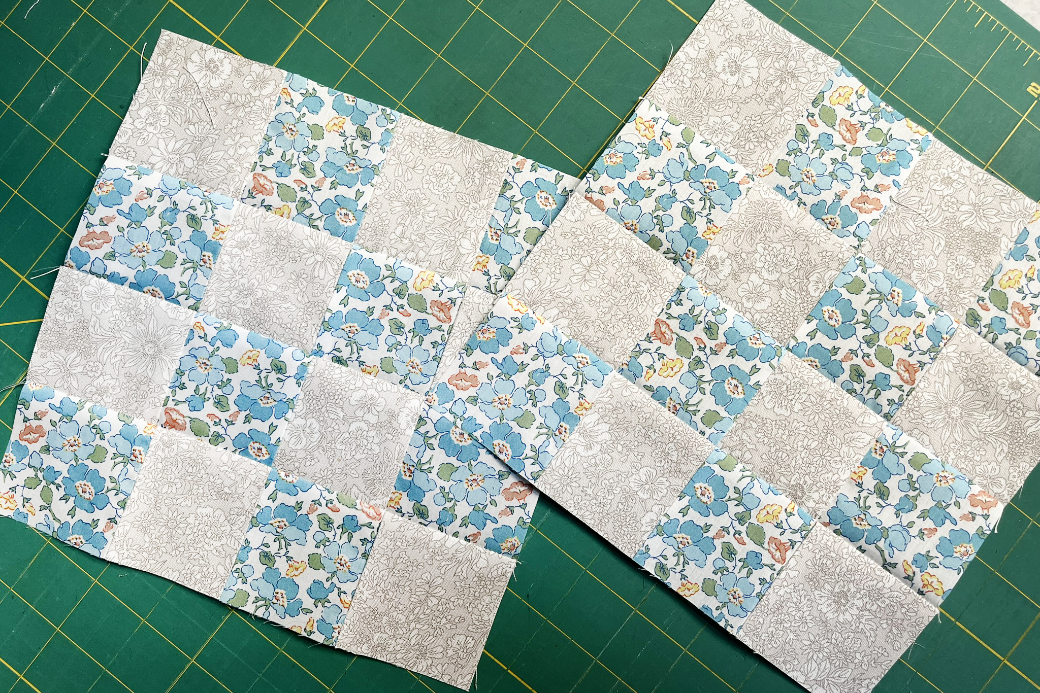 Two 16-patch quilt blocks on a sewing table. 