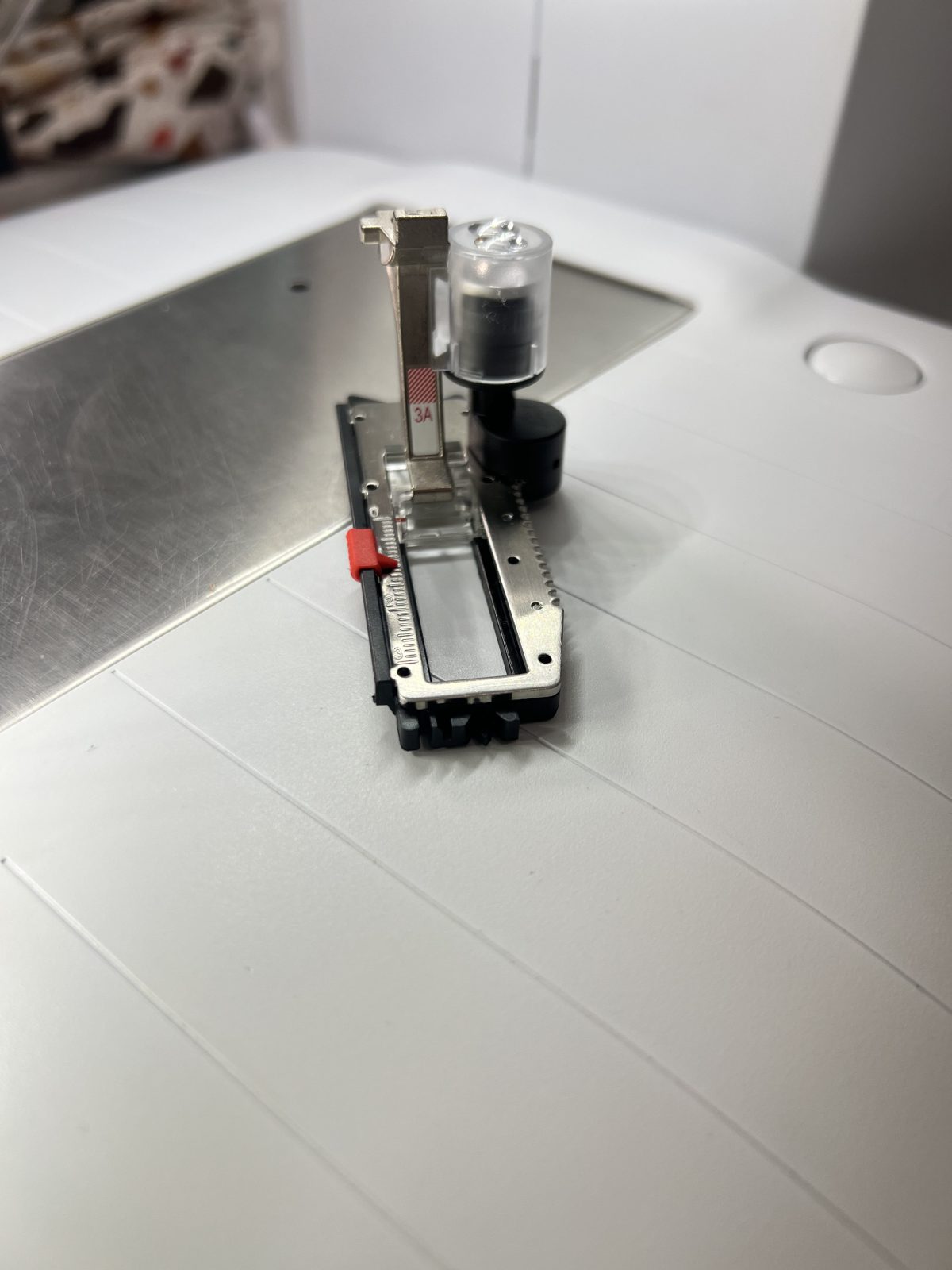 Close-up of a BERNINA 3A presser foot with automatic buttonhole sensor, sitting on a sewing machine