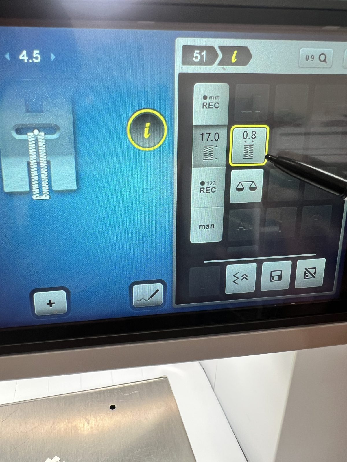 Close-up of a BERNINA sewing machine touchscreen showing buttonhole stitch settings, with a stylus pointing at the stitch width adjustment