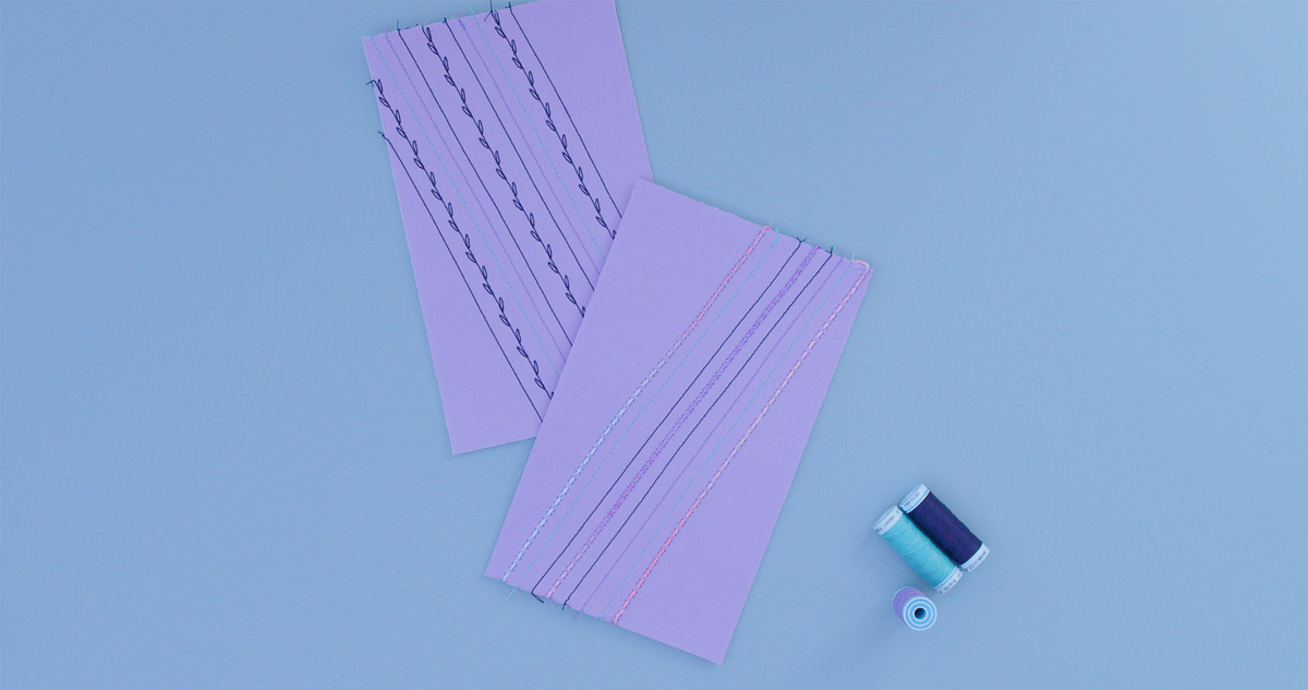 Purple fabric samples with decorative stitching alongside spools of navy and aqua thread