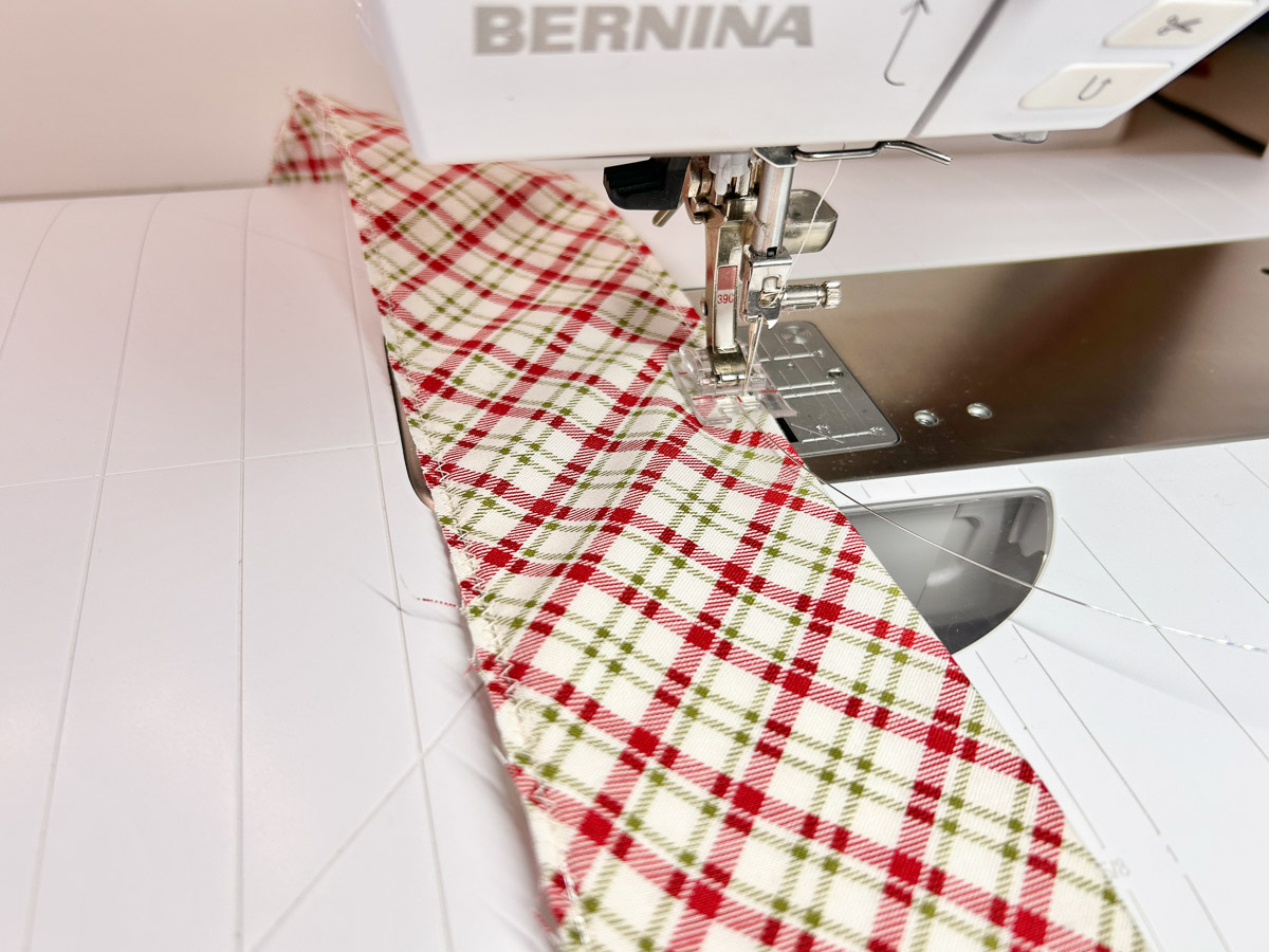 side view of wire being sew onto red plaid fabric.