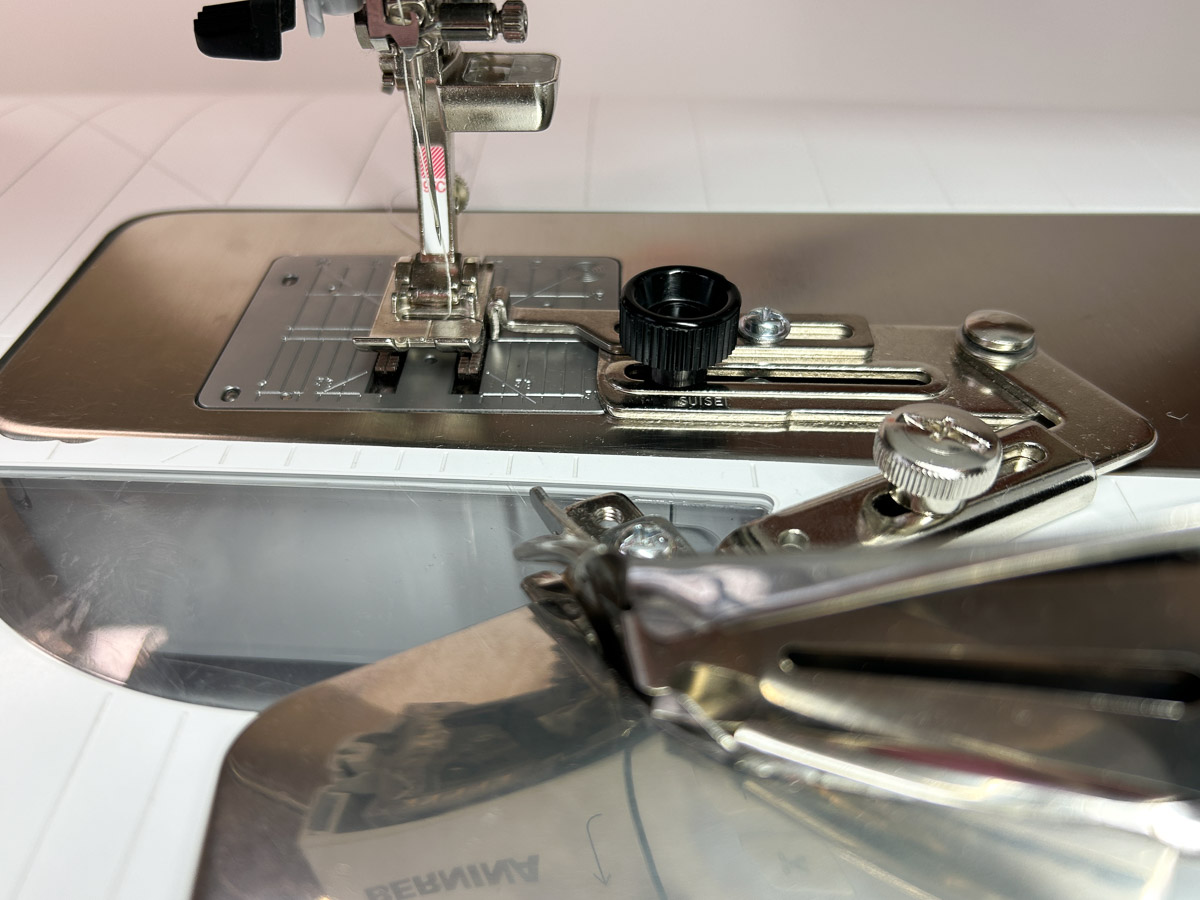 close up view of the binder attachment connected to the sewing machine stitch plate.