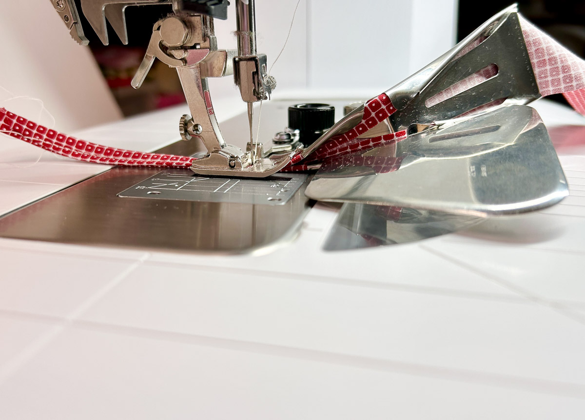 side view of binding fabric being fed through the sewing machine.