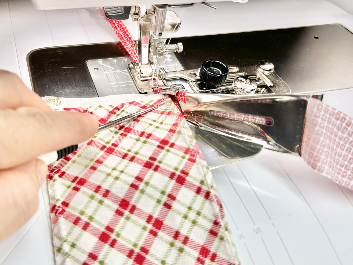 close up view of fabric being pushed through the binding channel with a stiletto.