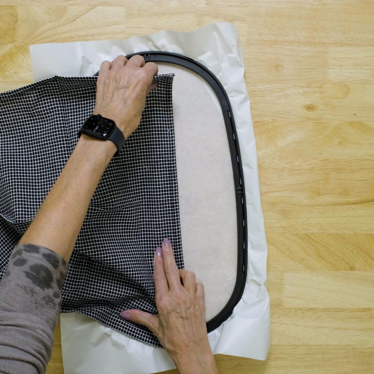 overhead view of a towel being aligned to the stitched placement line on hooped stabilizer