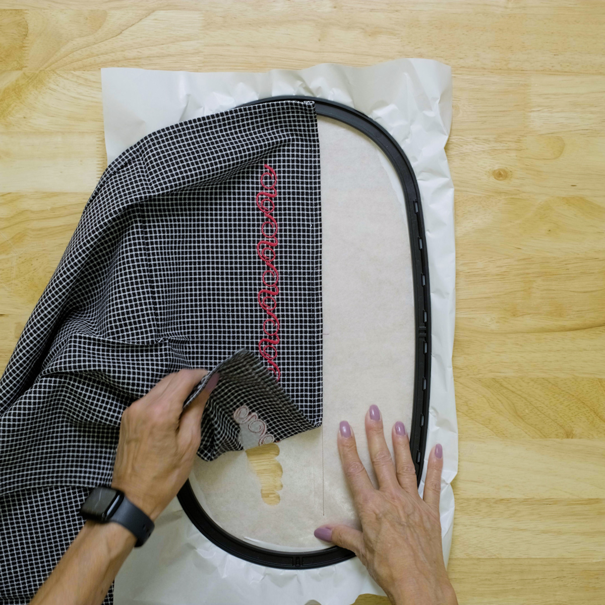 overhead view of hands removing the embroidered tea towel from stabilizer
