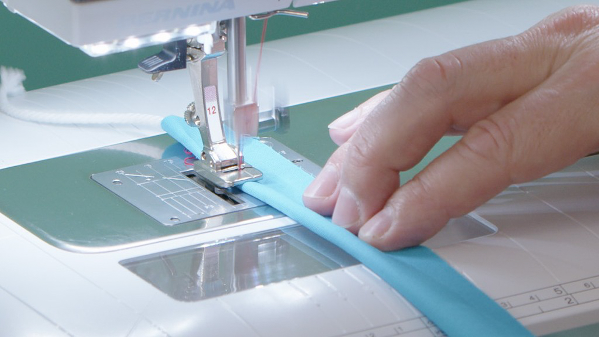 Blue fabric-wrapped cording being fed through the BERNINA sewing machine